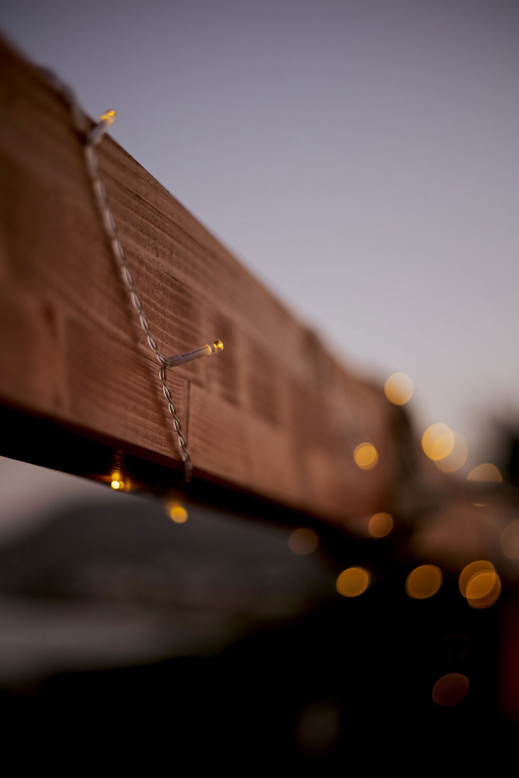 Nahaufnahme einer Outdoor-Solarlichterkette, die um einen Holzbalken gewickelt ist, mit unscharfem Hintergrund in der Abenddämmerung.