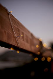 Nahaufnahme einer Outdoor-Solarlichterkette, die um einen Holzbalken gewickelt ist, mit unscharfem Hintergrund in der Abenddämmerung.