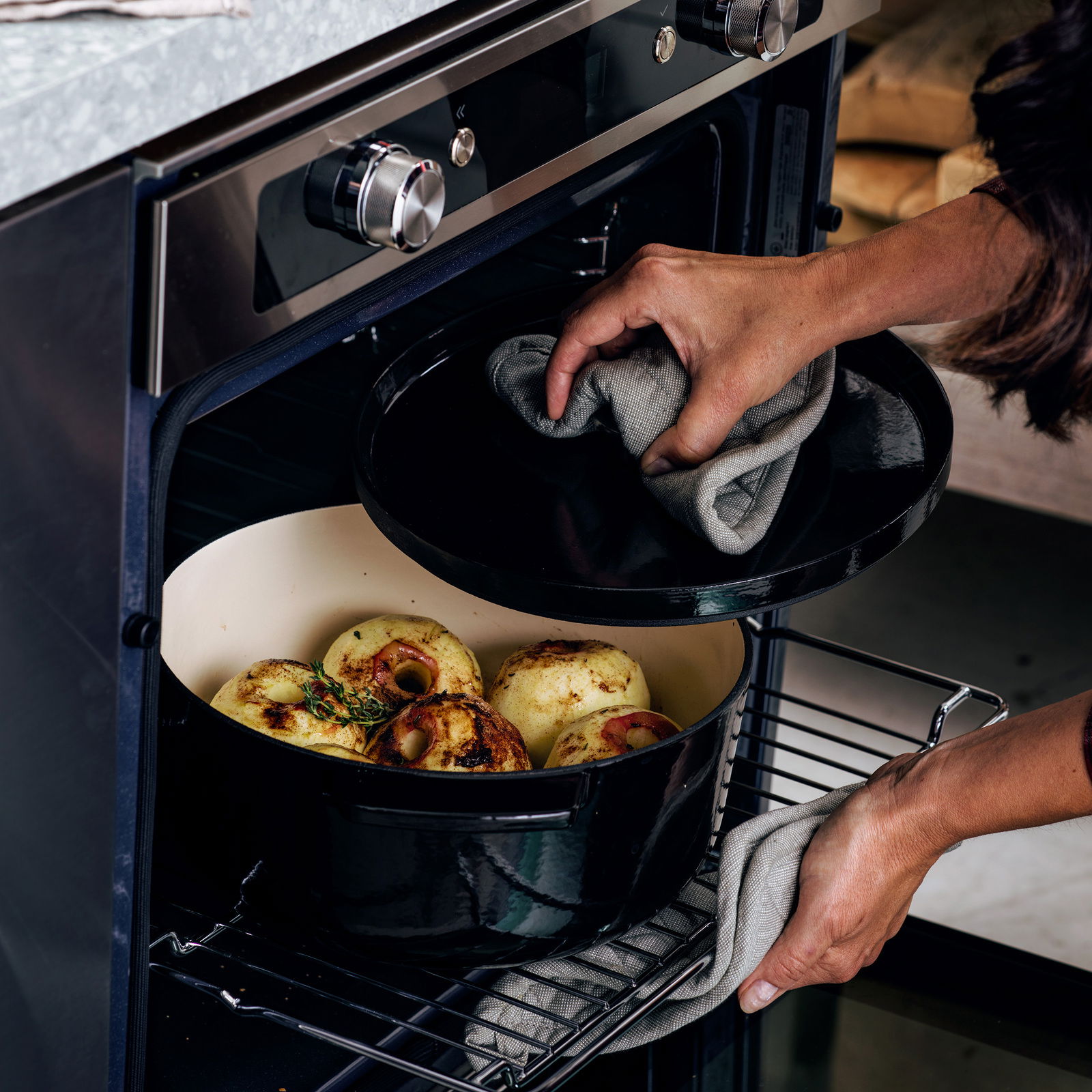 Gusseiserner Bräter rund 26cm in einem Ofen, gefüllt mit gefüllten Äpfeln, aus der Perspektive von vorne.