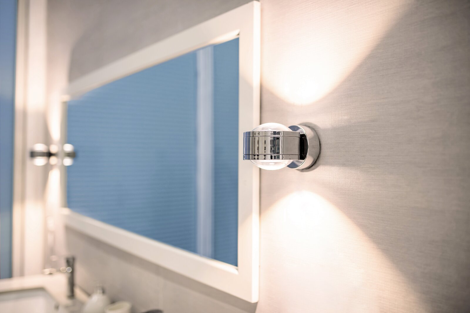 LED-Wandleuchte DUE PUNTO - UP & DOWN in seitlicher Perspektive an einer Wand montiert, mit Lichtstrahlen nach oben und unten.