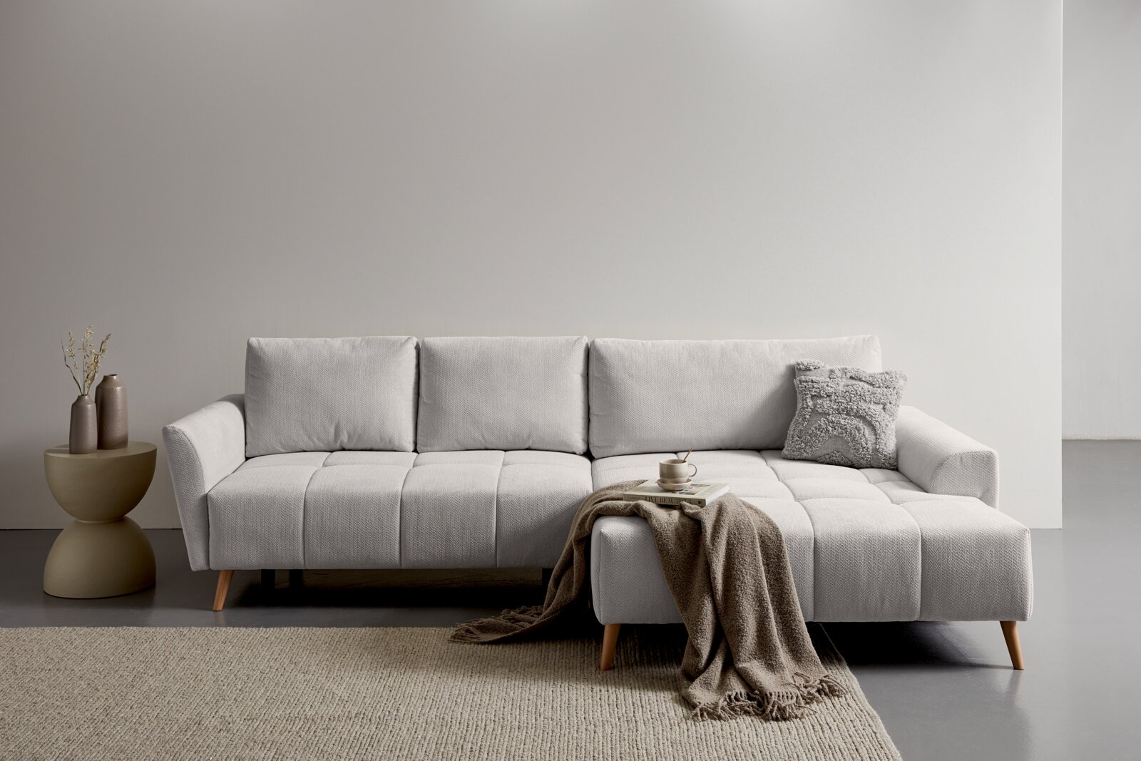 Z2 Ecksofa ZELDA Helles, modern gepolstertes Sofa mit Recamiere rechts und Holzfüßen in minimalistischer Wohnszene; Frontansicht auf Augenhöhe.