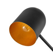 Nahaufnahme einer modernen Stehleuchte mit schwarzem Lampenschirm und goldener Innenseite, seitliche Perspektive.