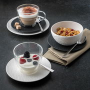 Drei stilvolle Becher auf einem dunklen Tisch, gefüllt mit Cappuccino, Joghurt mit Beeren und Müsli, aus der Vogelperspektive.