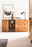 Holz-Sideboard mit Schubladen und Glastür, dekoriert mit einer Vase und Lampe, aus frontaler Perspektive.