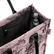 Nahaufnahme einer offenen Einkaufstasche mit floralem Muster, einer Wasserflasche und einem Reißverschlussfach, von oben betrachtet.