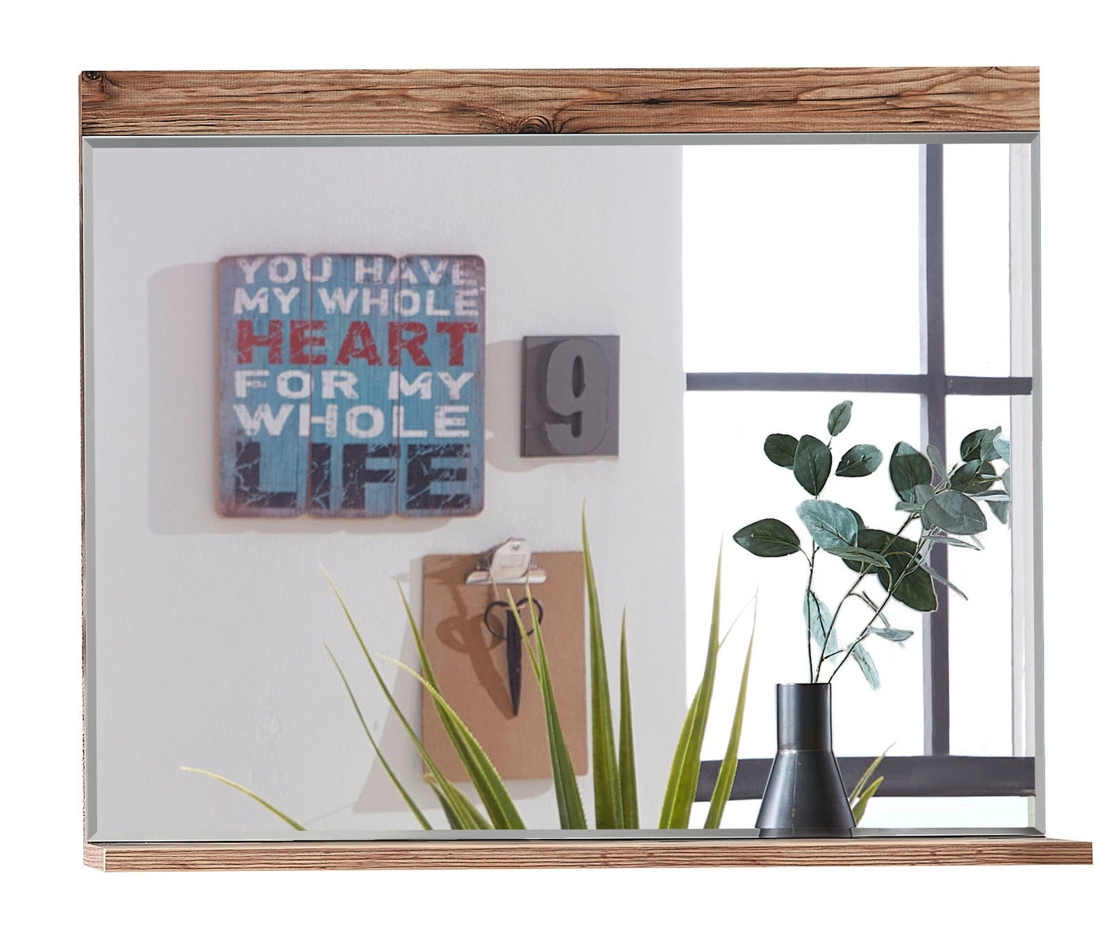 Spiegel mit Holzrahmen, reflektiert eine Wanddekoration mit Schriftzug und eine Pflanze in einer Vase, Perspektive von vorne