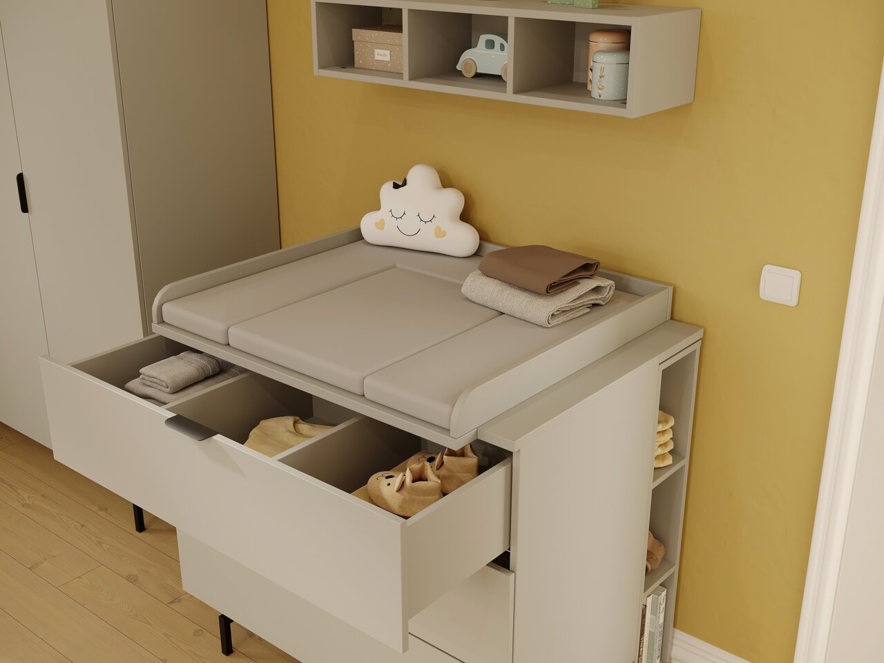 Een commode in een babykamer, met een geopende lade en planken, gefotografeerd vanuit een zijaanzicht.