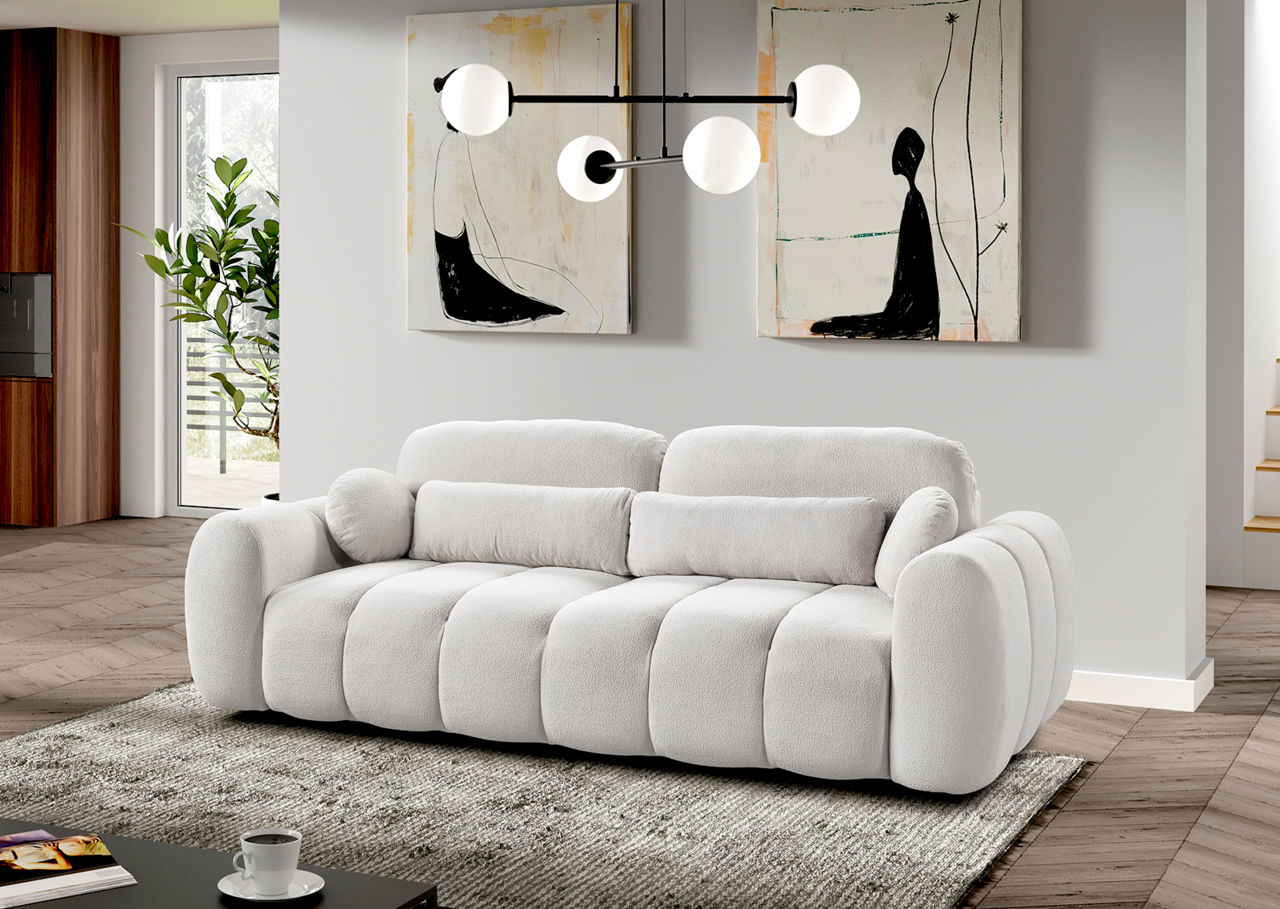 Modernes Funktionssofa in hellem Stoff, frontal fotografiert in einem stilvoll eingerichteten Wohnzimmer mit Kunstwerken an der Wand und einer modernen Hängelampe.