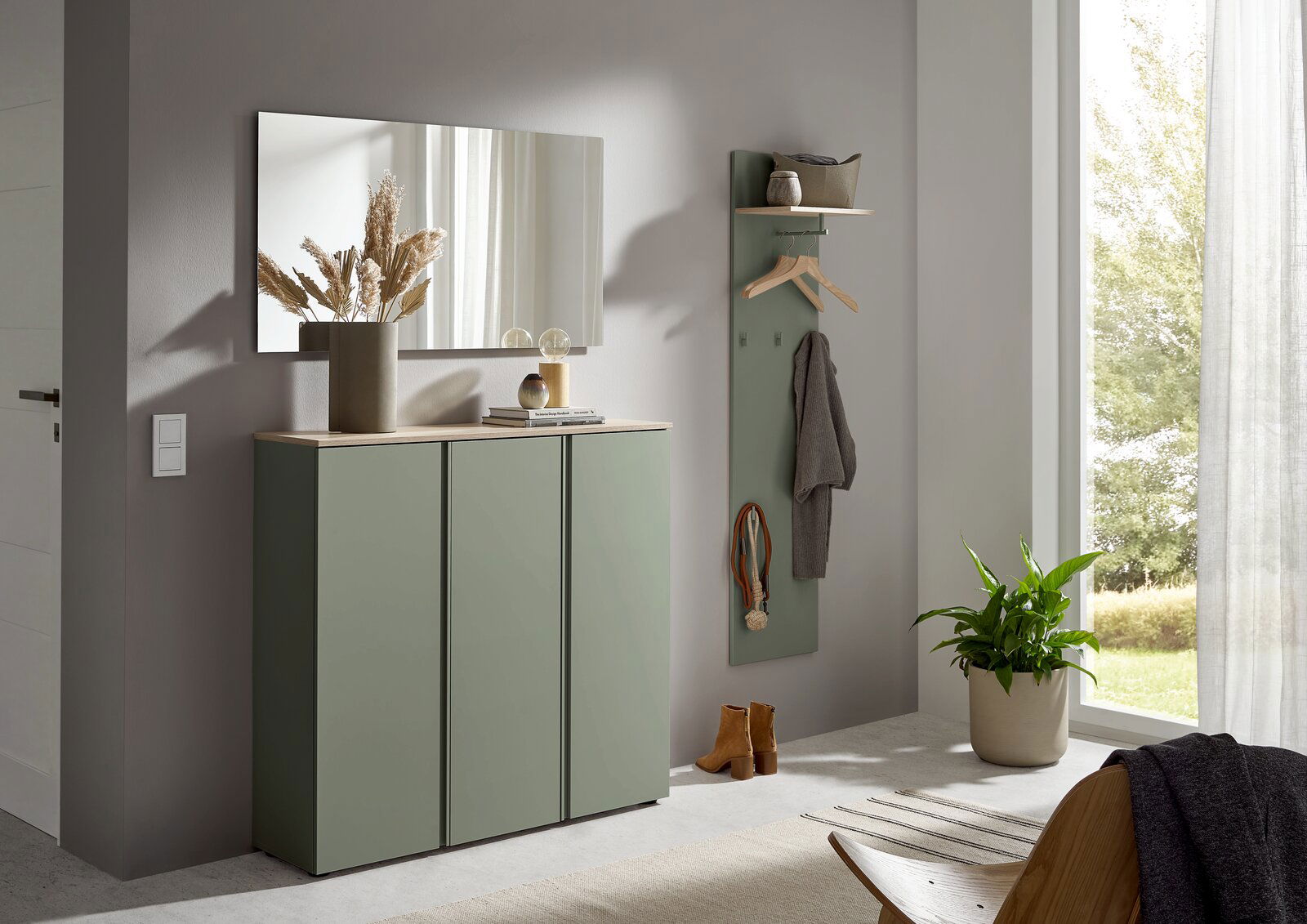 Modernes Flur-Set mit grünem Schuhschrank mit Holzoptik-Deckplatte, Wandgarderobe mit Ablage und Spiegel an grauer Wand, seitliche Frontansicht im hellen Eingangsbereich