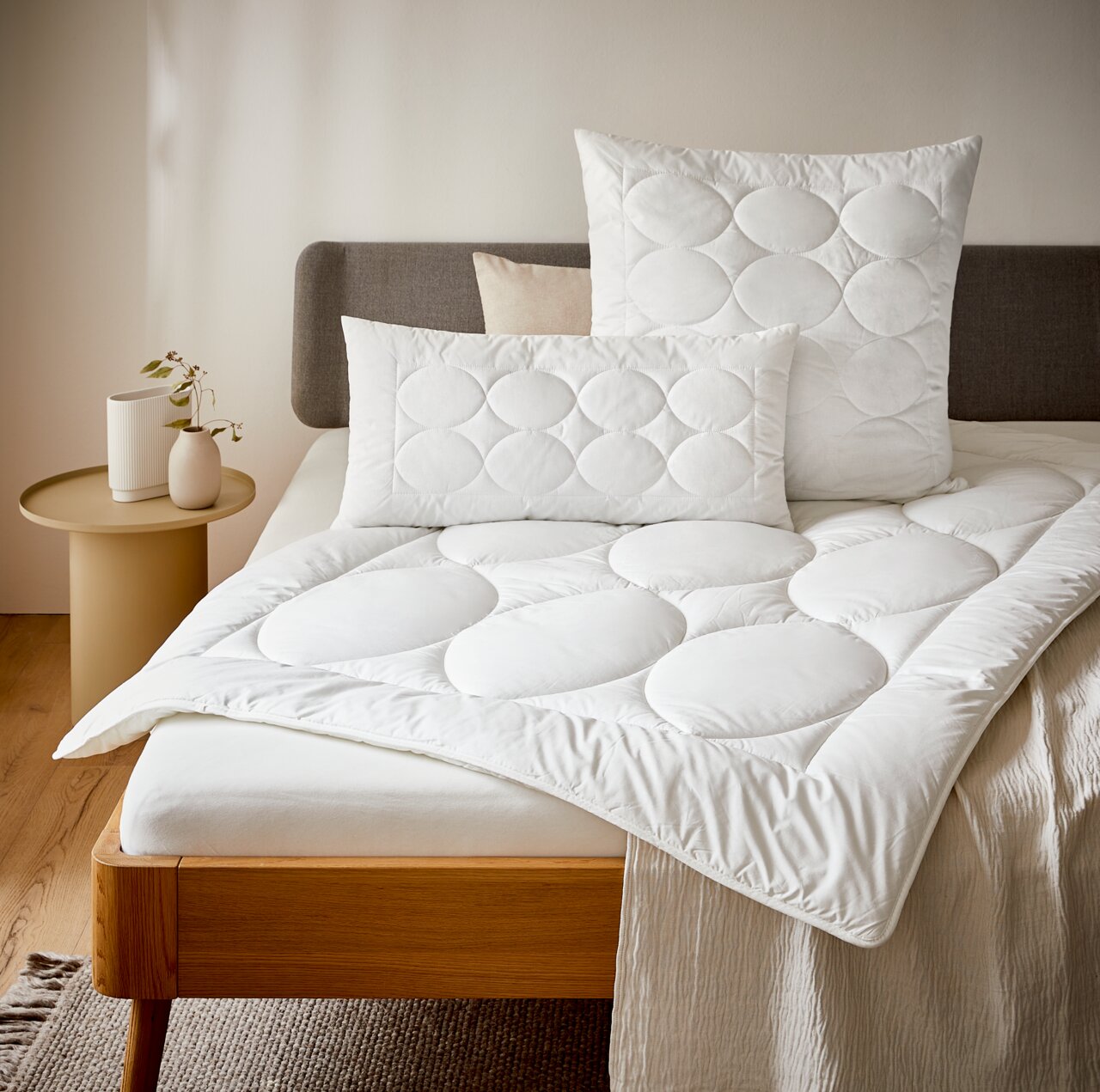 Bio-Vio Ganzjahresbett TENDRE Gemütliches Schlafzimmer mit einem Bett, das mit einer weißen Ganzjahresbettdecke und passenden Kissen in Nahaufnahme dekoriert ist.
