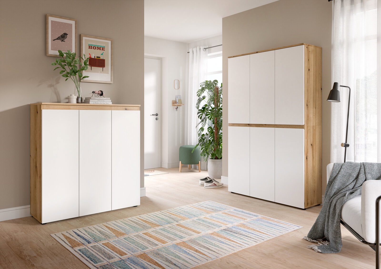 Heller Wohnraum mit modernem Schrank-Set in Weiß und Holzoptik, links ein niedriges Sideboard und rechts ein hoher Schrank, beide in frontaler Perspektive leicht von links fotografiert.