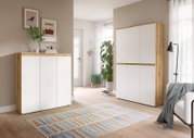 Heller Wohnraum mit modernem Schrank-Set in Weiß und Holzoptik, links ein niedriges Sideboard und rechts ein hoher Schrank, beide in frontaler Perspektive leicht von links fotografiert.