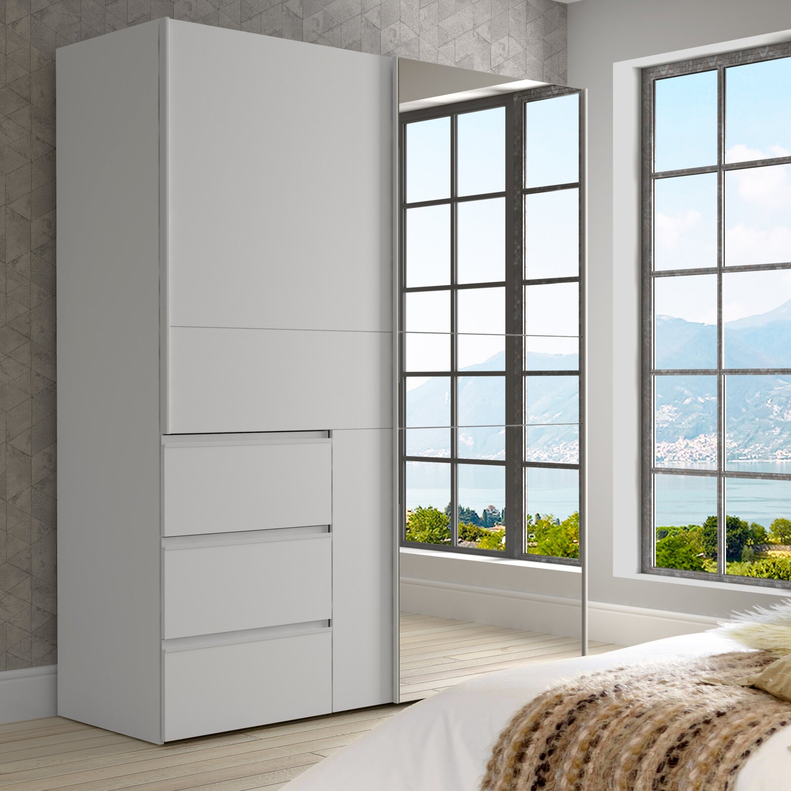 Moderner weißer Schwebetürenschrank mit zwei Türen, einer davon mit Spiegel, in einem hellen Raum mit Blick auf große Fenster. Perspektive von schräg vorne.