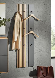 Moderne Paneel-Leiste in Holzoptik mit Haken, frontal an einer Betonwand montiert, ideal zum Aufhängen von Kleidung.