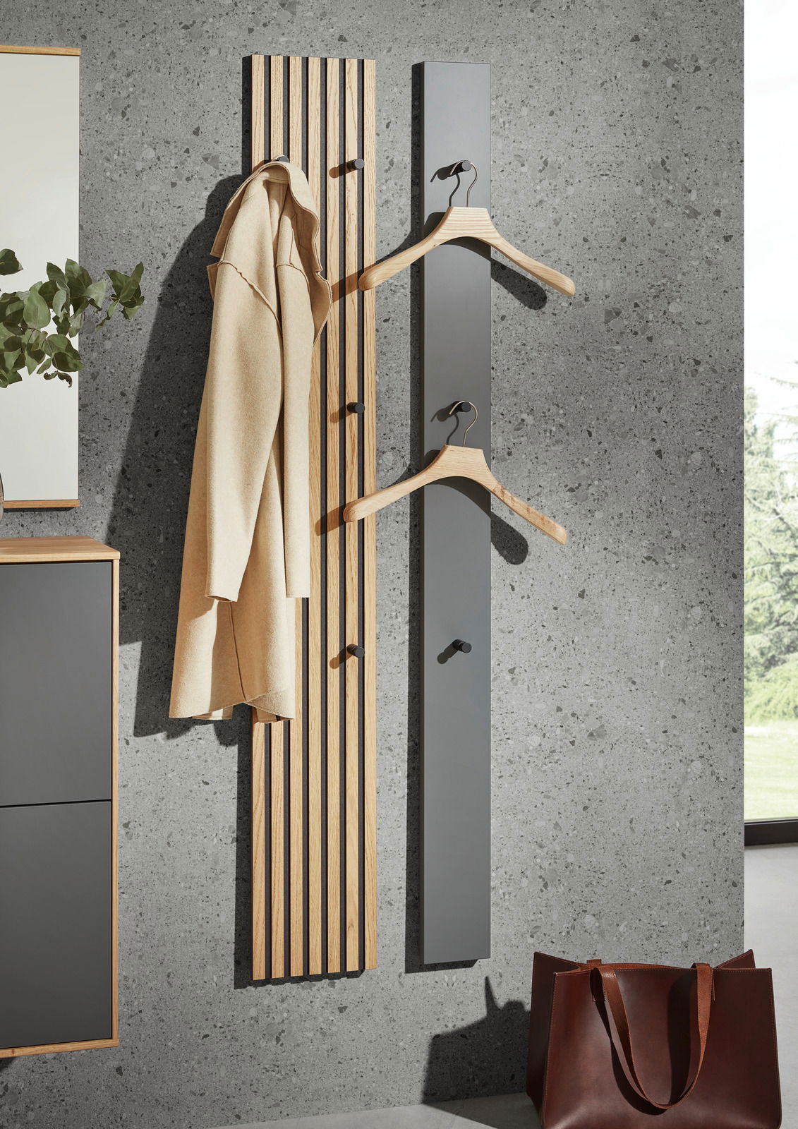 Moderne Paneel-Leiste in Holzoptik mit Haken, frontal an einer Betonwand montiert, ideal zum Aufhängen von Kleidung.