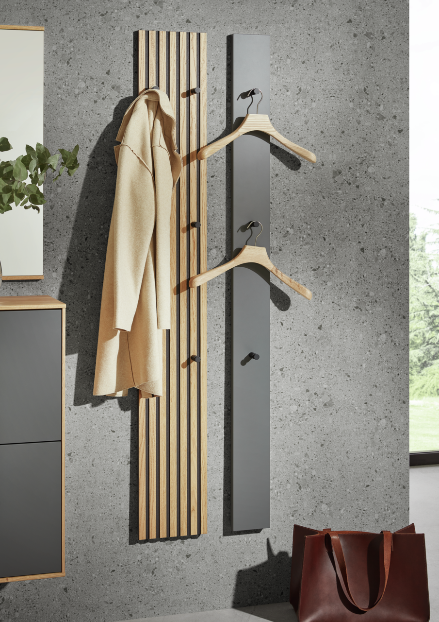 Moderne Paneel-Leiste in Holzoptik mit Haken, frontal an einer Betonwand montiert, ideal zum Aufhängen von Kleidung.
