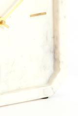 Nahaufnahme einer eleganten Uhr mit einem Zifferblatt aus weißem Marmor und goldenen Zeigern, seitliche Perspektive.