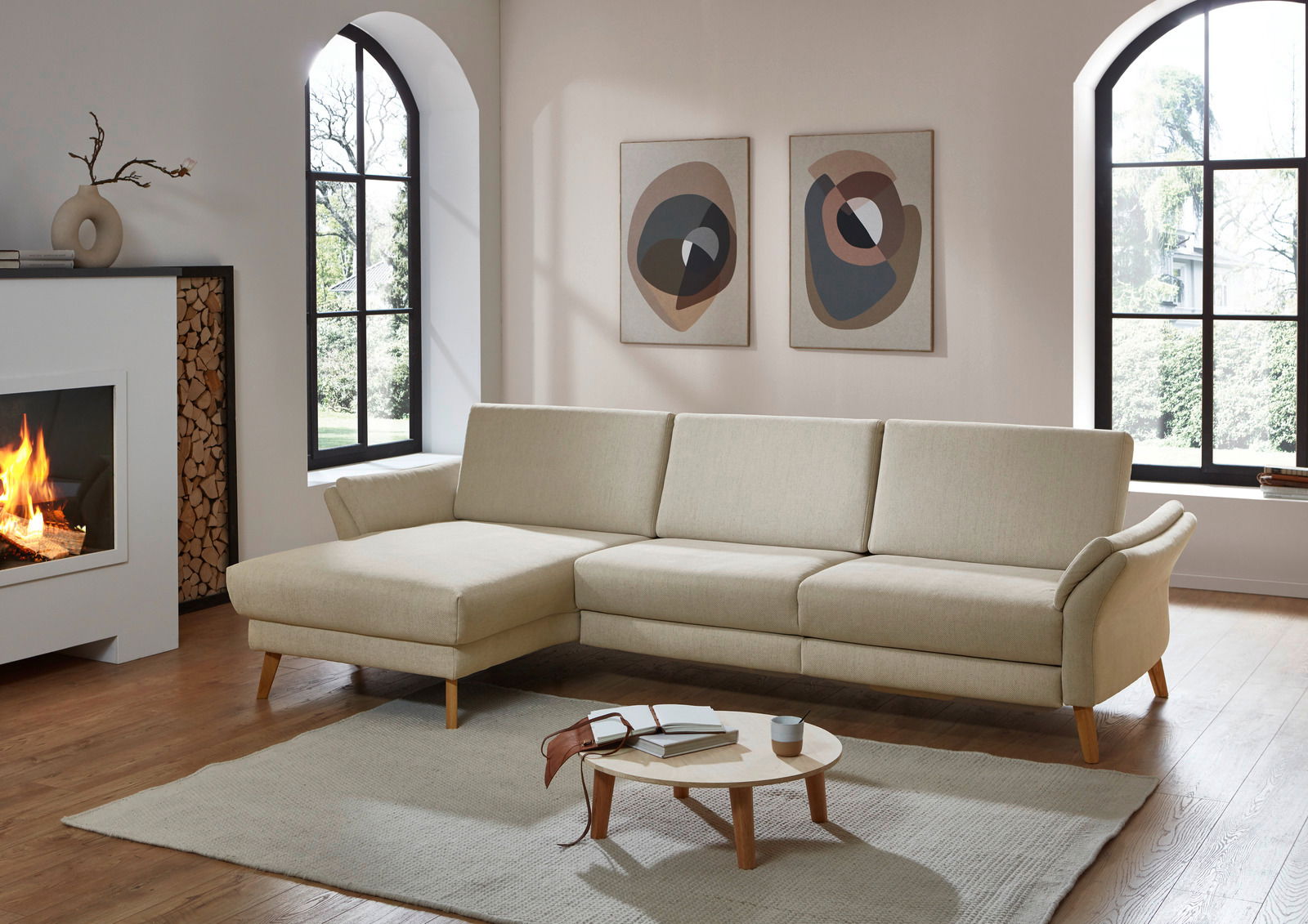 Beige Longchairkombination Valnatura LIGNUM in einem modernen Wohnzimmer, seitliche Perspektive mit Kamin und dekorativen Bildern an der Wand.