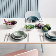 Frühstückstisch mit verschiedenen Tellern und Schalen in Blau- und Grüntönen, gefüllt mit frischem Gemüse und Obst, aus der Vogelperspektive.