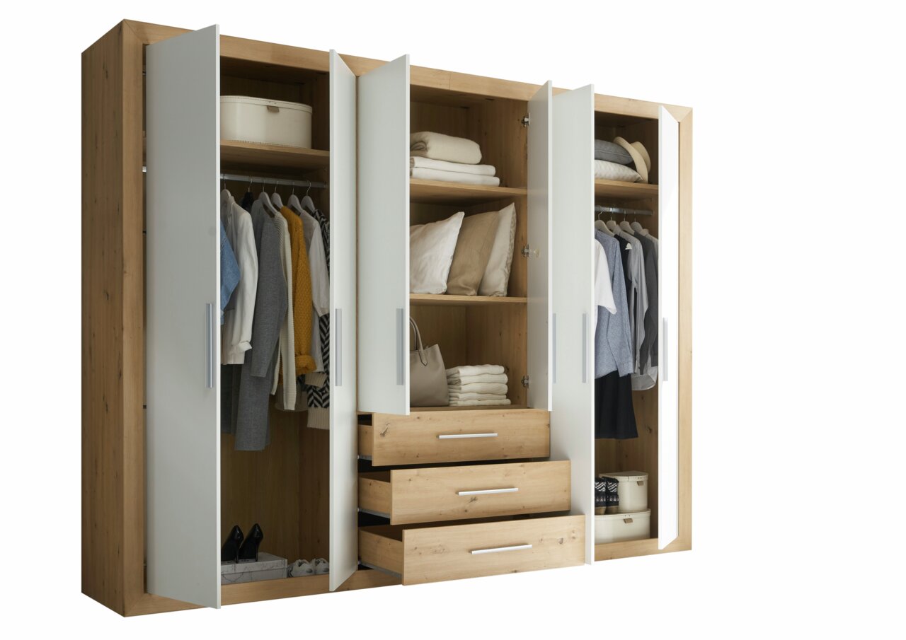 Sechstüriger Drehtürenschrank aus Holz mit weißen Türen, teilweise geöffnet, zeigt Kleidung, Regale und Schubladen, Perspektive von vorne.