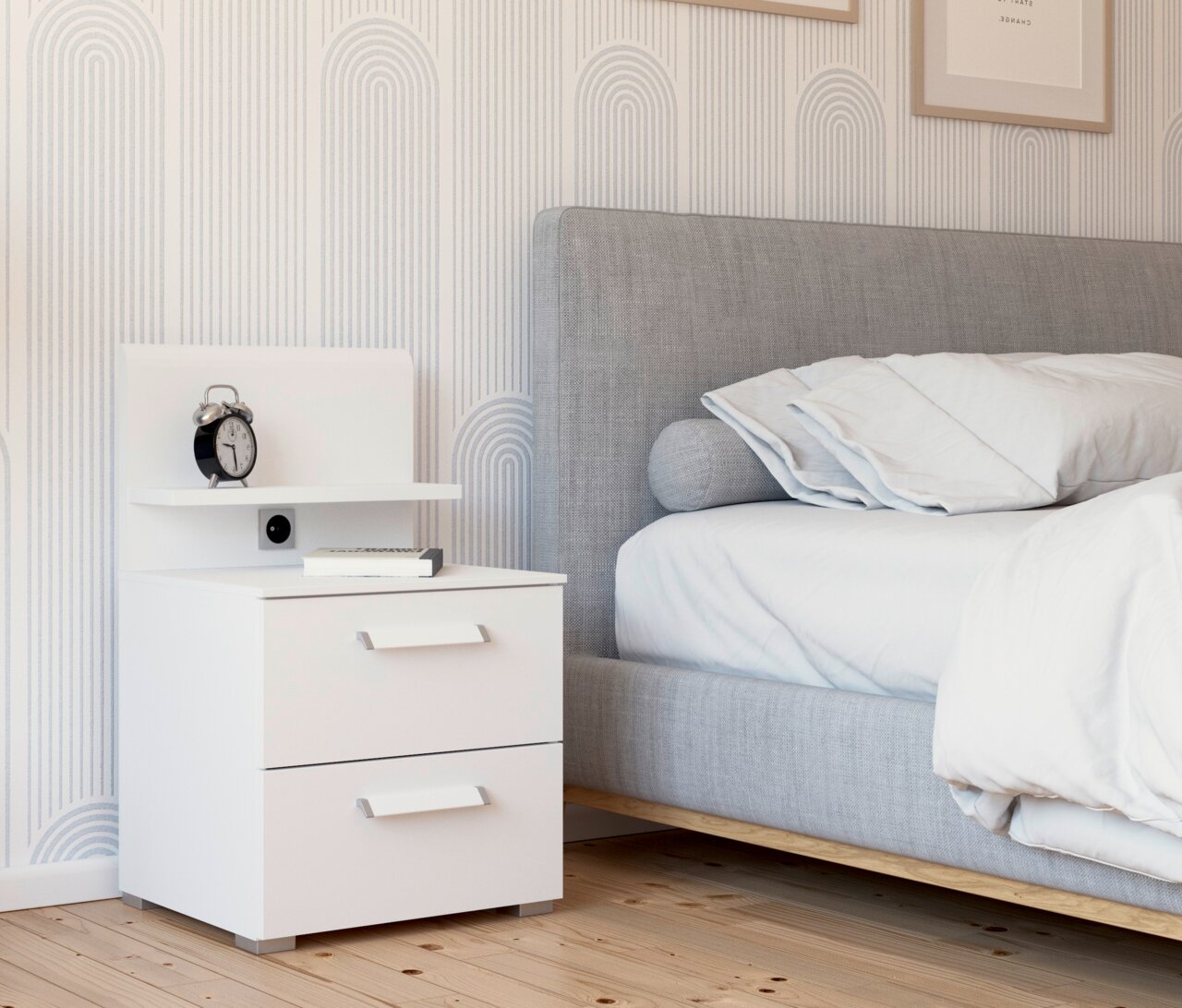 Weißes Nachttisch-Paneel mit zwei Schubladen, einem Regal und einer Steckdose, seitliche Perspektive neben einem grauen Bett.