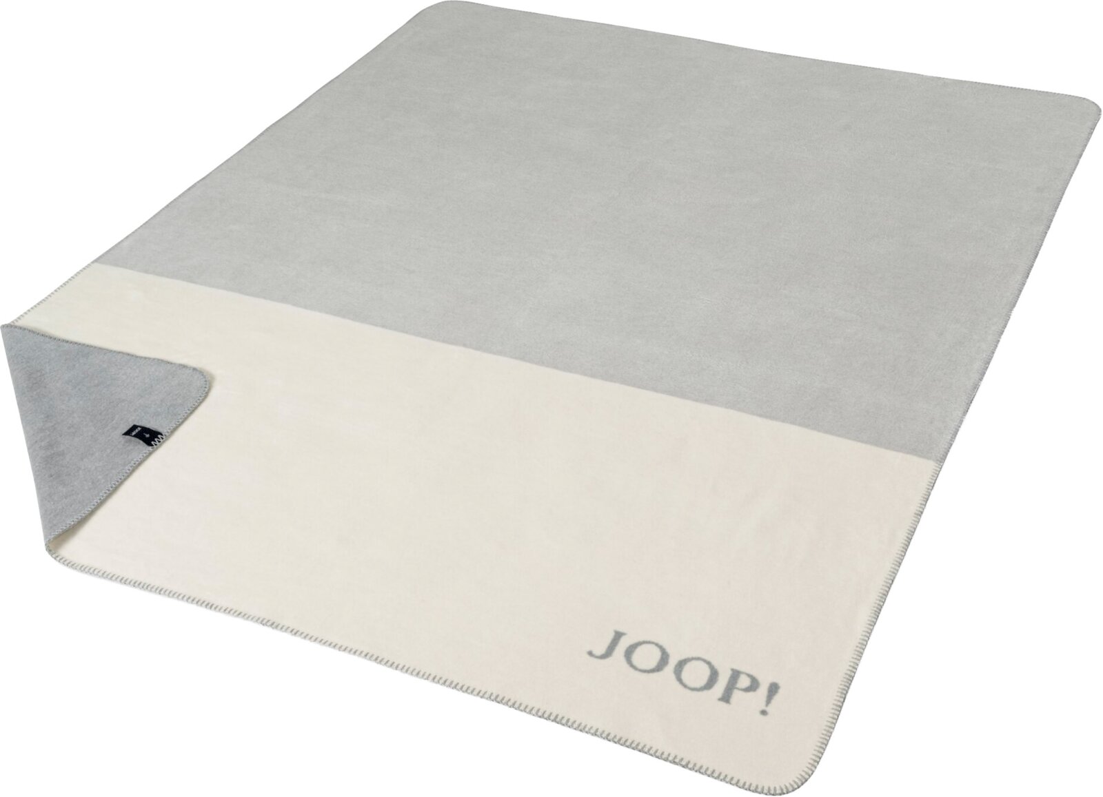 Zweifarbige Joop! Wohndecke in Grau und Creme mit umgeschlagener Ecke und Logostickerei, schräg von oben (3/4-Ansicht) fotografiert