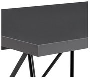 Nahaufnahme eines modernen Winkelschreibtischs mit schwarzer Oberfläche und schrägen Metallbeinen, seitliche Perspektive.