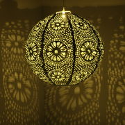 Hängende Solar Laterne mit filigranem Muster, das ein warmes Licht und dekorative Schatten an die Wand wirft, seitliche Perspektive