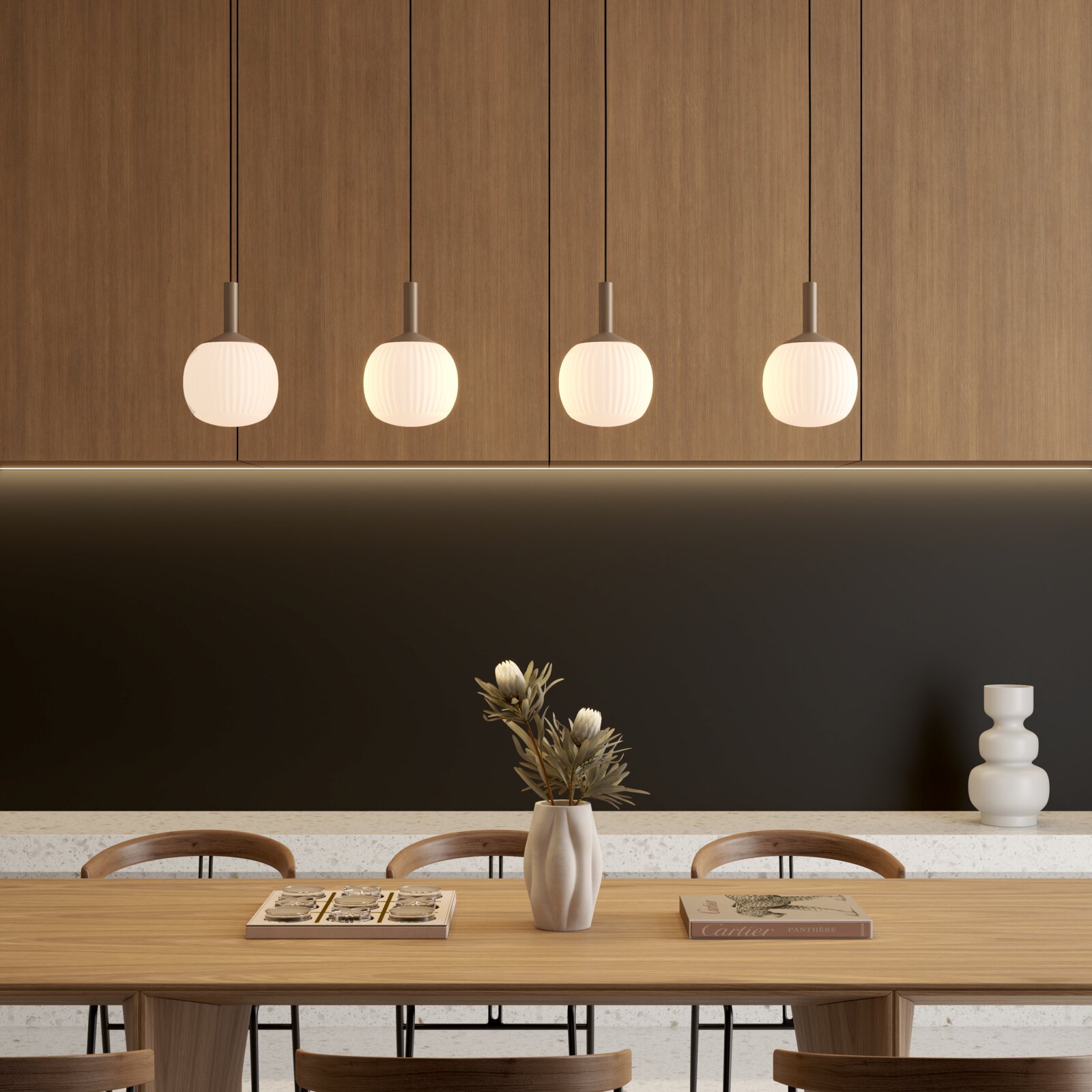 Moderne Esszimmer-Szene mit vier runden, geriffelten Pendelleuchten über einem Holztisch, Vase mit Trockenblumen und Deko auf dem Tisch, frontal aus Augenhöhe aufgenommen.