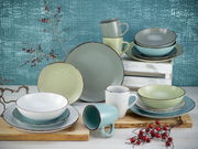 Kombiservice 16-tlg. Fashion in sanften Pastelltönen, bestehend aus Tellern, Schalen und Tassen, auf einem Tisch mit dekorativen Zweigen und Beeren, seitliche Perspektive.