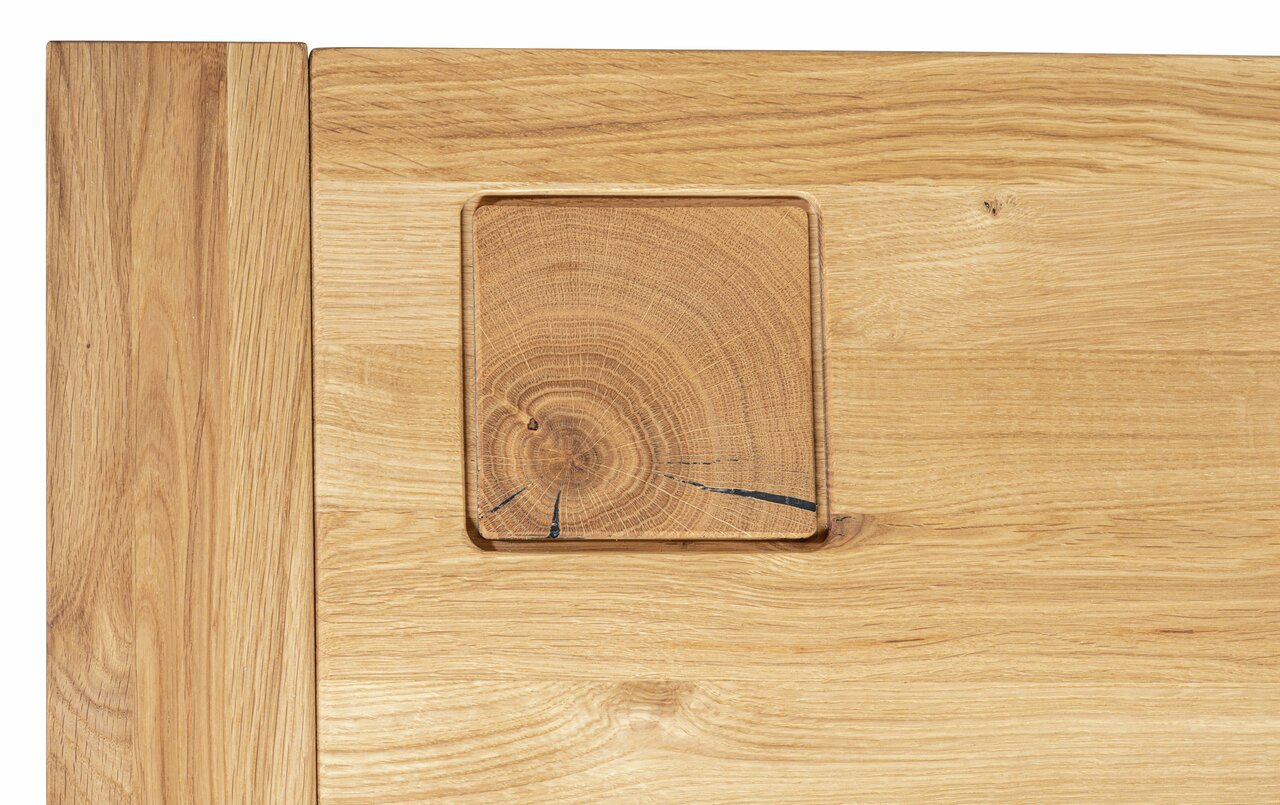 Detailfoto van een salontafel van lichtgekleurd hout met zichtbare houtnerf en een vierkant houten inzetstuk.