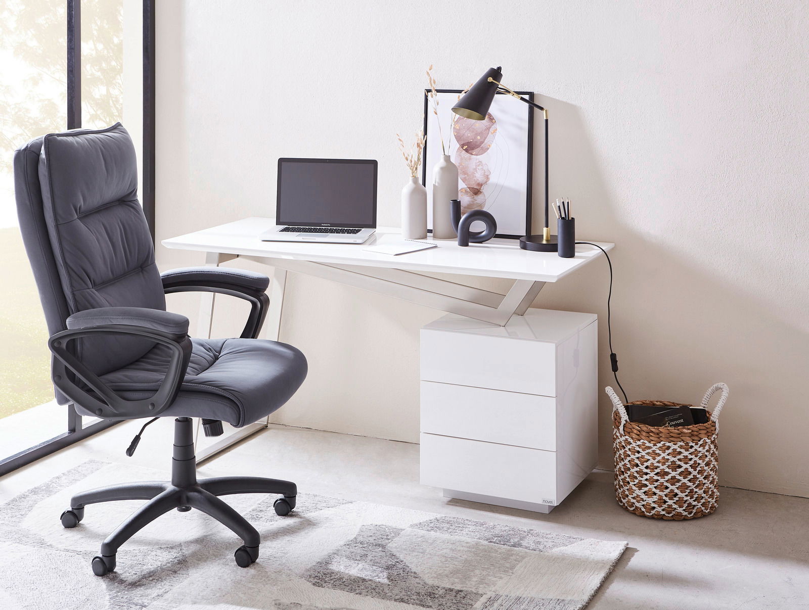 Moderner Schreibtisch mit weißer Oberfläche, seitlicher Perspektive, ausgestattet mit Laptop, Lampe und Dekorationen, neben einem ergonomischen Bürostuhl.