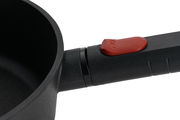 Nahaufnahme einer schwarzen Guss-Hochrandpfanne mit rotem Knopf am Griff, seitliche Perspektive.