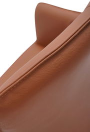 Nahaufnahme eines braunen Armlehnstuhls aus Leder, seitliche Perspektive