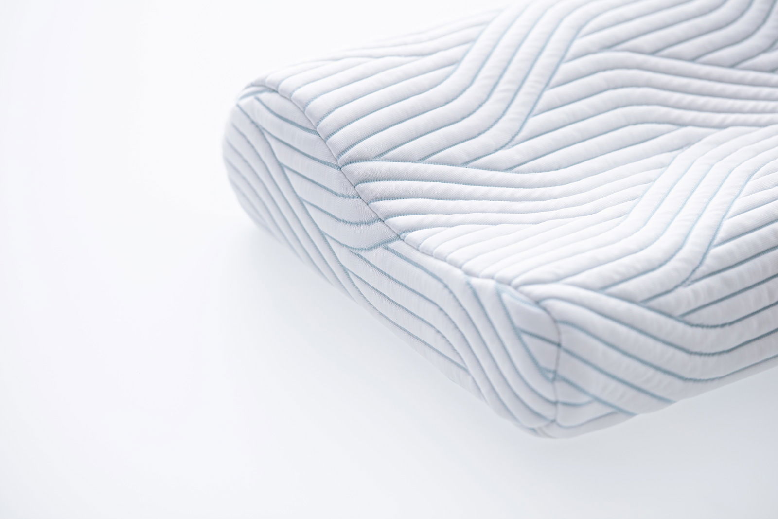 Nahaufnahme eines ergonomischen Schlafkissens mit gestepptem Muster, seitliche Perspektive