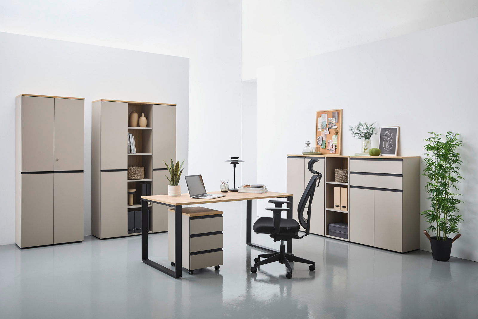 Moderne Büromöbel in einem hellen Raum, bestehend aus einem Winkelschreibtisch mit Rollcontainer, einem ergonomischen Bürostuhl und mehreren Aktenschränken. Perspektive von vorne.