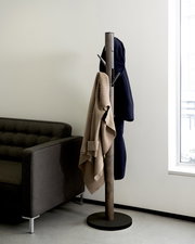 Moderner Garderobenständer Umbra Flapper in einem Wohnzimmer, seitliche Perspektive, mit Jacken und Pullover behängt.