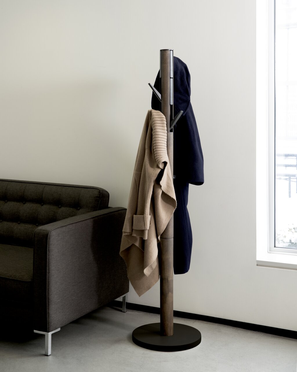Moderner Garderobenständer Umbra Flapper in einem Wohnzimmer, seitliche Perspektive, mit Jacken und Pullover behängt.