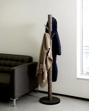 Moderner Garderobenständer Umbra Flapper in einem Wohnzimmer, seitliche Perspektive, mit Jacken und Pullover behängt.