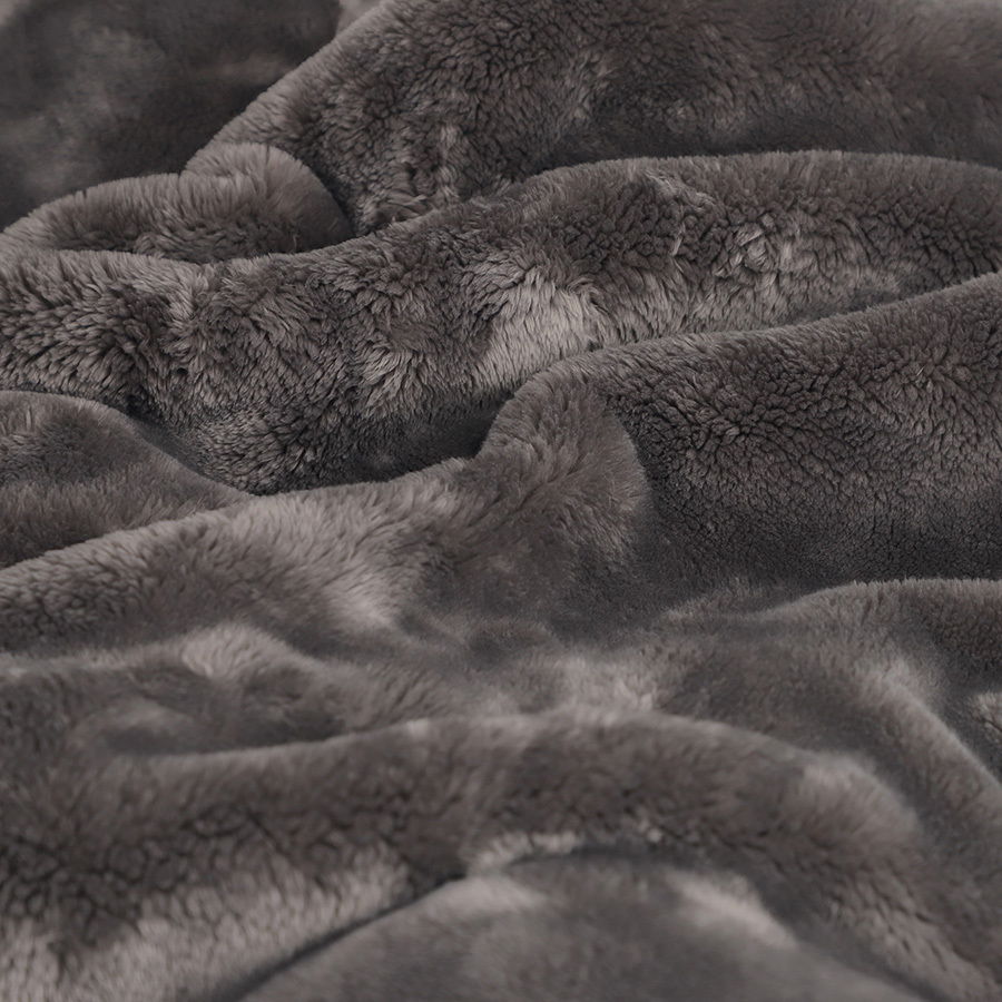Nahaufnahme einer flauschigen, grauen Wohndecke in welliger Anordnung.