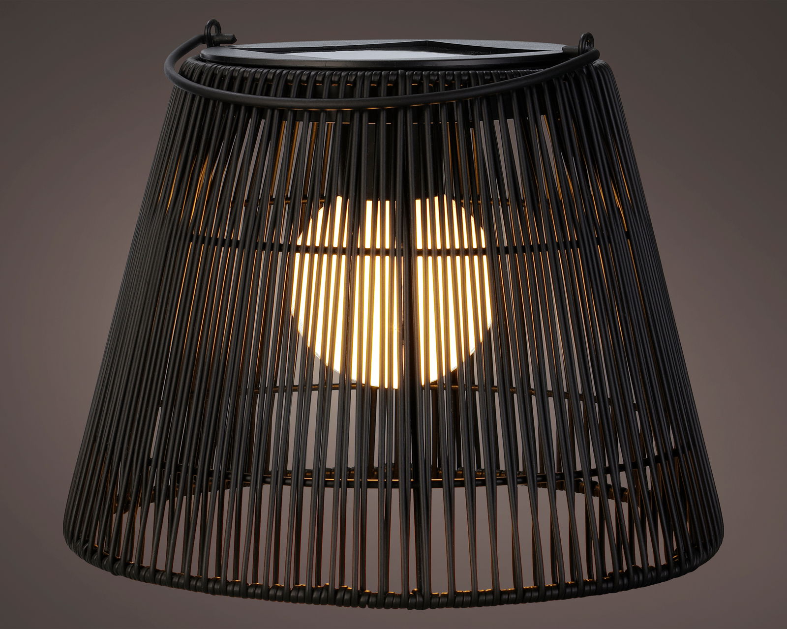 Nahaufnahme einer schwarzen Solar Laterne mit Korbdesign, die von innen beleuchtet ist.