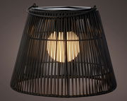 Nahaufnahme einer schwarzen Solar Laterne mit Korbdesign, die von innen beleuchtet ist.