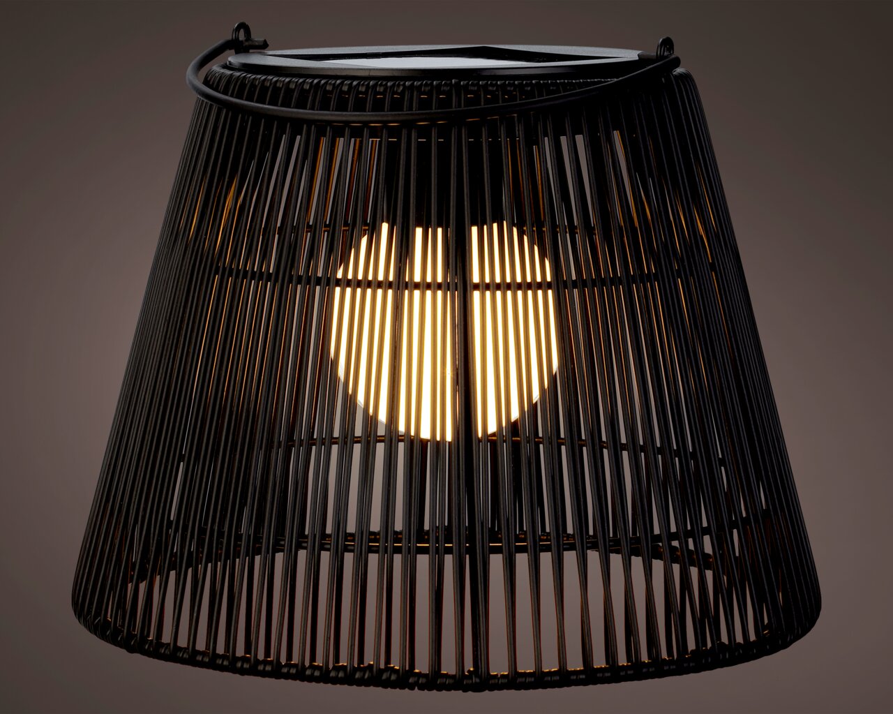 Nahaufnahme einer schwarzen Solar Laterne mit Korbdesign, die von innen beleuchtet ist.