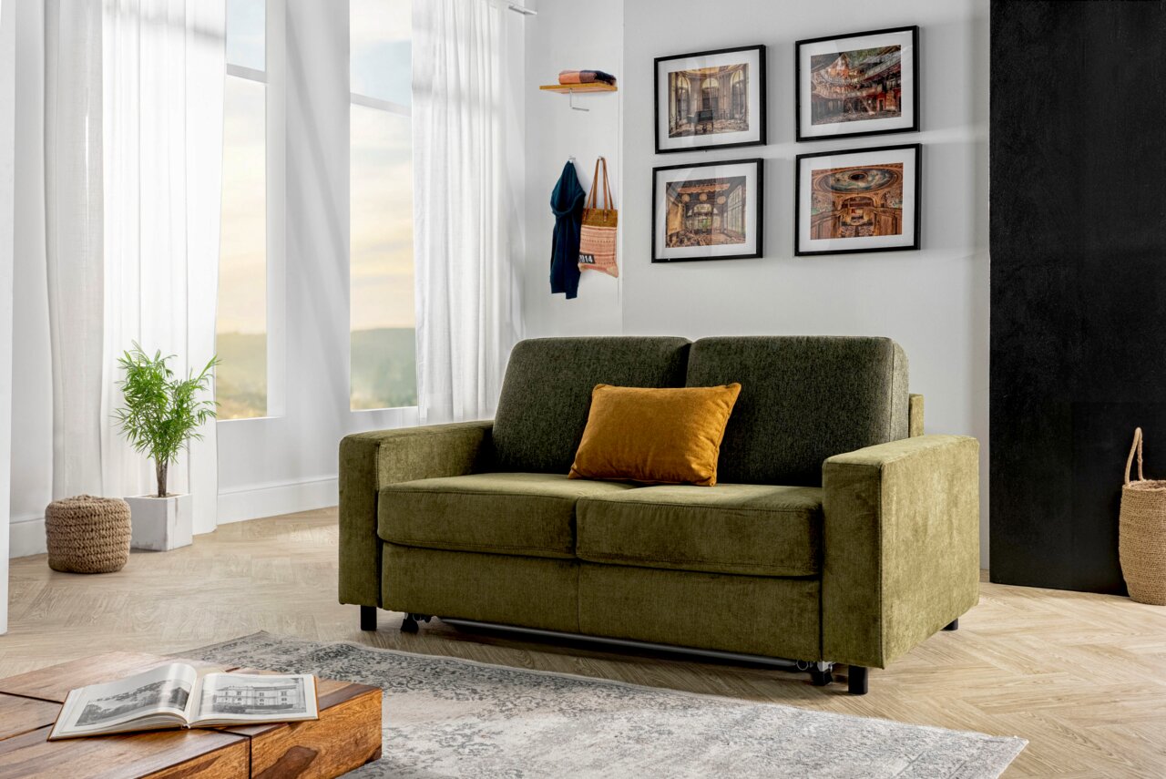 Groene functionele bank met een geel kussen in een moderne woonkamer, gezien vanaf de zijkant.