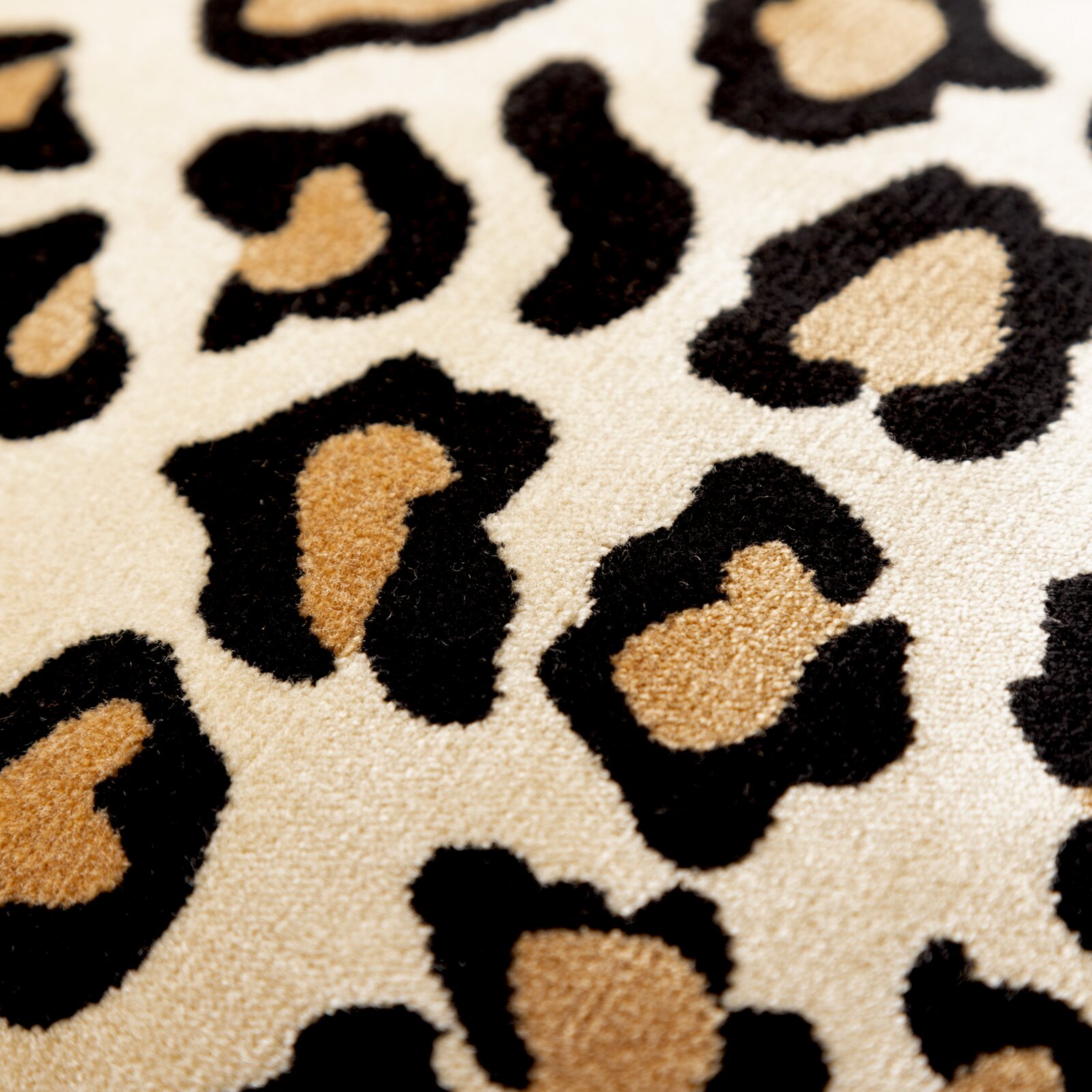 Close-up van een sierkussen met luipaardprint in beige, zwart en bruin.