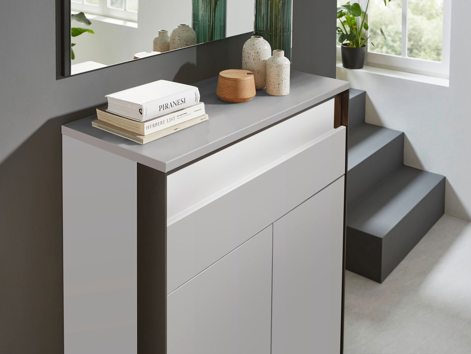 Moderner Schuhschrank in hellem Raum, seitliche Perspektive, dekoriert mit Büchern und Vasen.