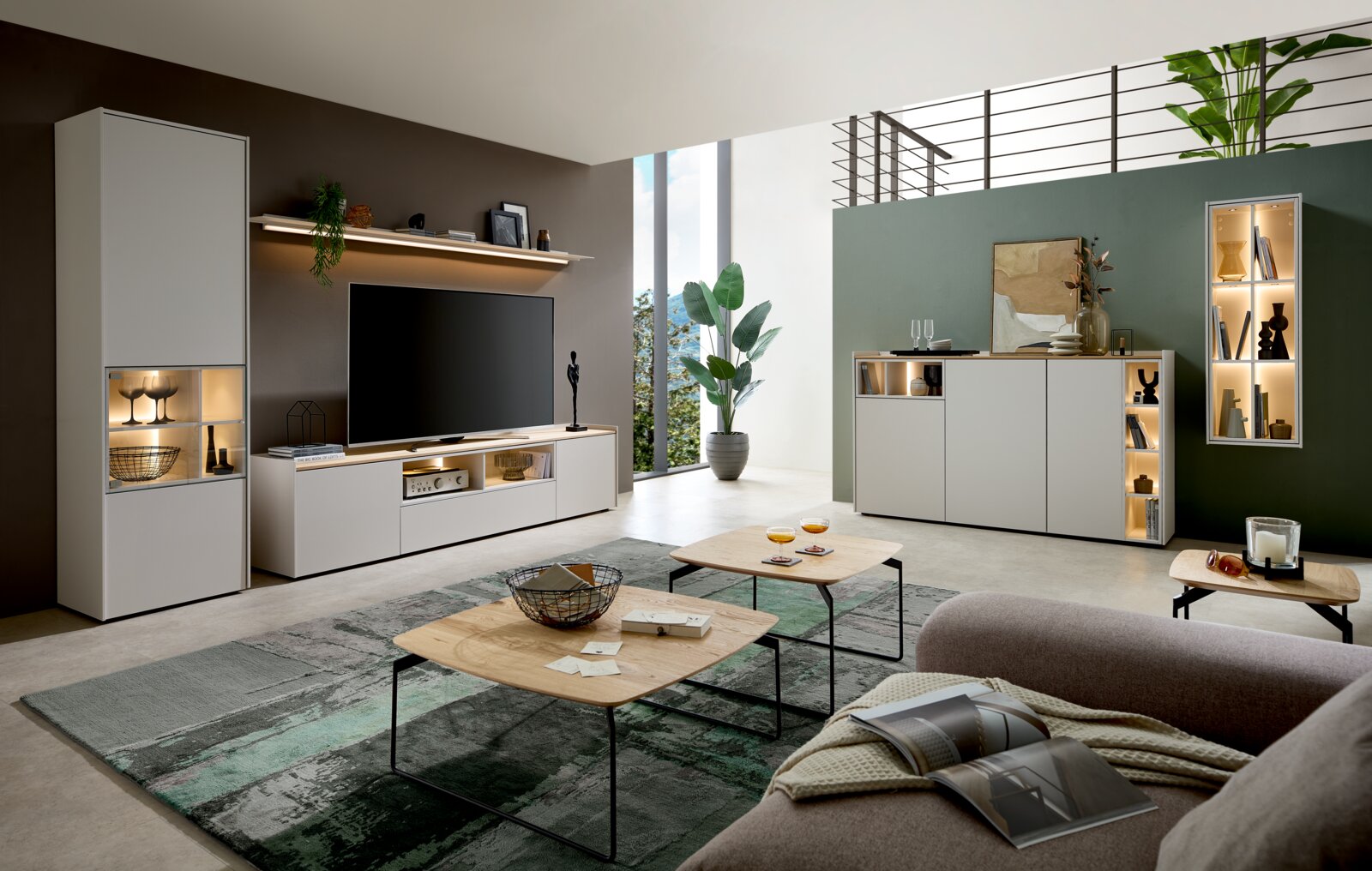 Modern lichtgrijs woonkamermeubelprogramma met tv-meubel, hoge kast, dressoir en verlichte vitrinekast, vanuit schuin vooraanzicht in een stijlvol interieur