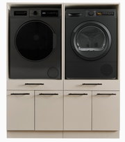 Schwarze Frontlader-Waschmaschine und Wäschetrockner nebeneinander in einem weißen Einbauschrank mit Schubladen, Frontansicht auf die Geräte.