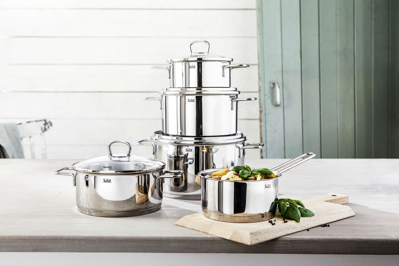 Topfset Alicante 5-tlg aus Edelstahl, bestehend aus mehreren Töpfen mit Deckeln, auf einer Küchenarbeitsplatte präsentiert. Perspektive von vorne.