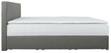 Seitliche Ansicht eines grauen Boxbetts mit weißer Matratze und Kopfteil.